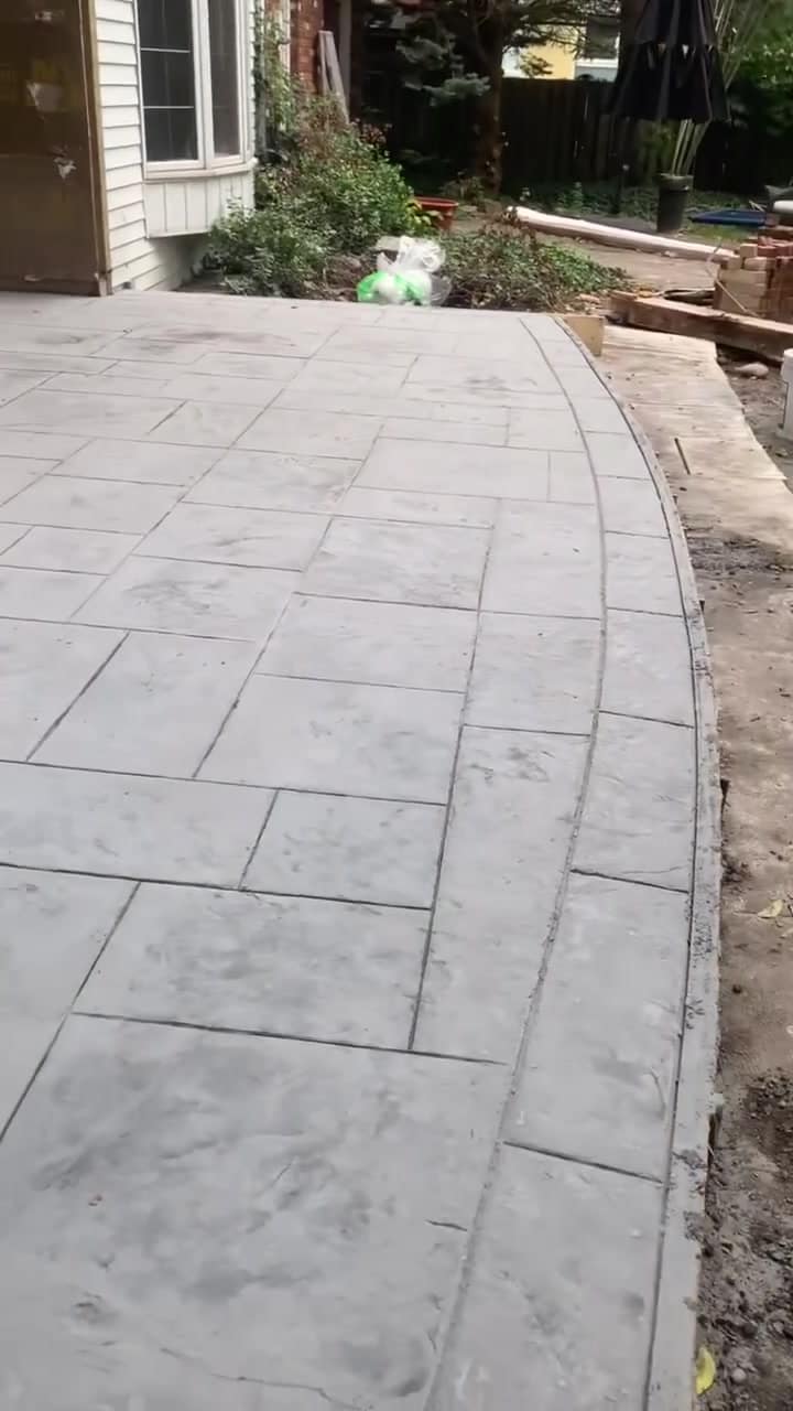 Stamped concrete walkway with a smooth border curving past a garden