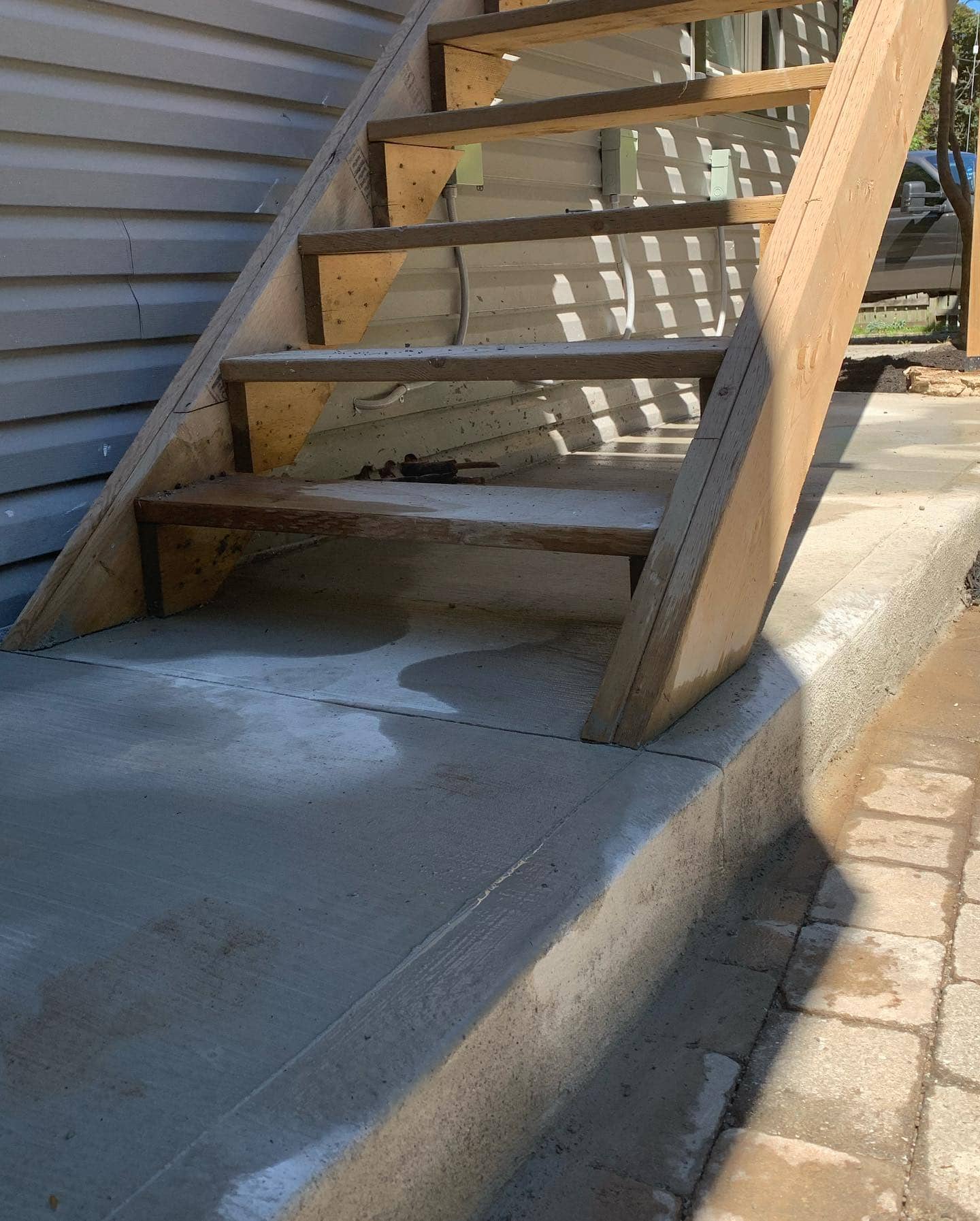 Broom finish concrete landing and steps with a wood staircase above